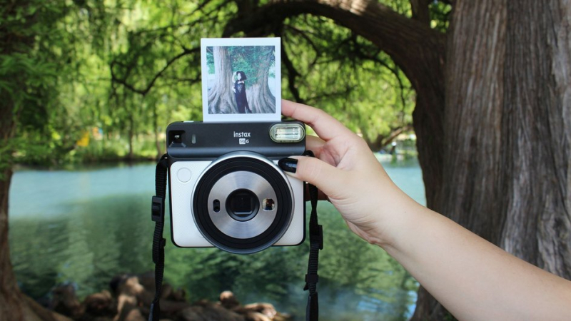 Девушка делает снимок на фотоаппарат моментальной печати